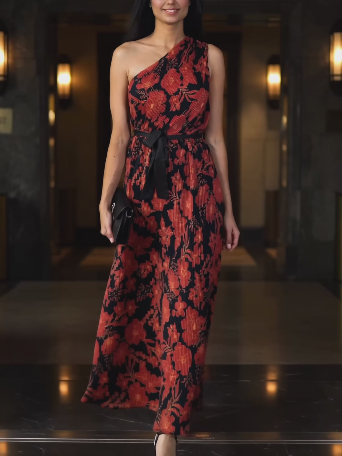 Floral pleated maxi dress moving through an evening entrance as the skirt swings and settles.