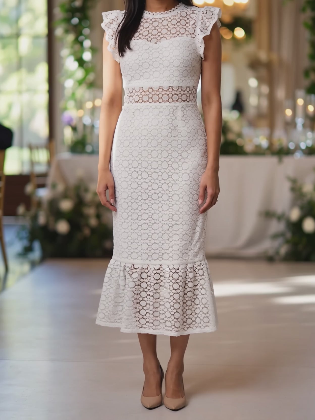 White lace midi dress moving through two short steps, showing the fitted skirt and fluttering scalloped hem.