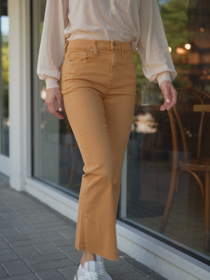 Gold cropped kick-flare pants moving through two walking steps in a café setting.