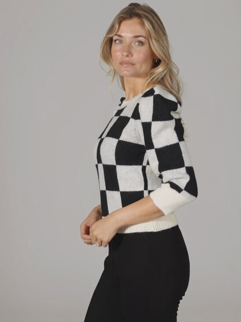 Checkmate Chic sweater in motion, showing its puff sleeves and fitted hem during a short turn.