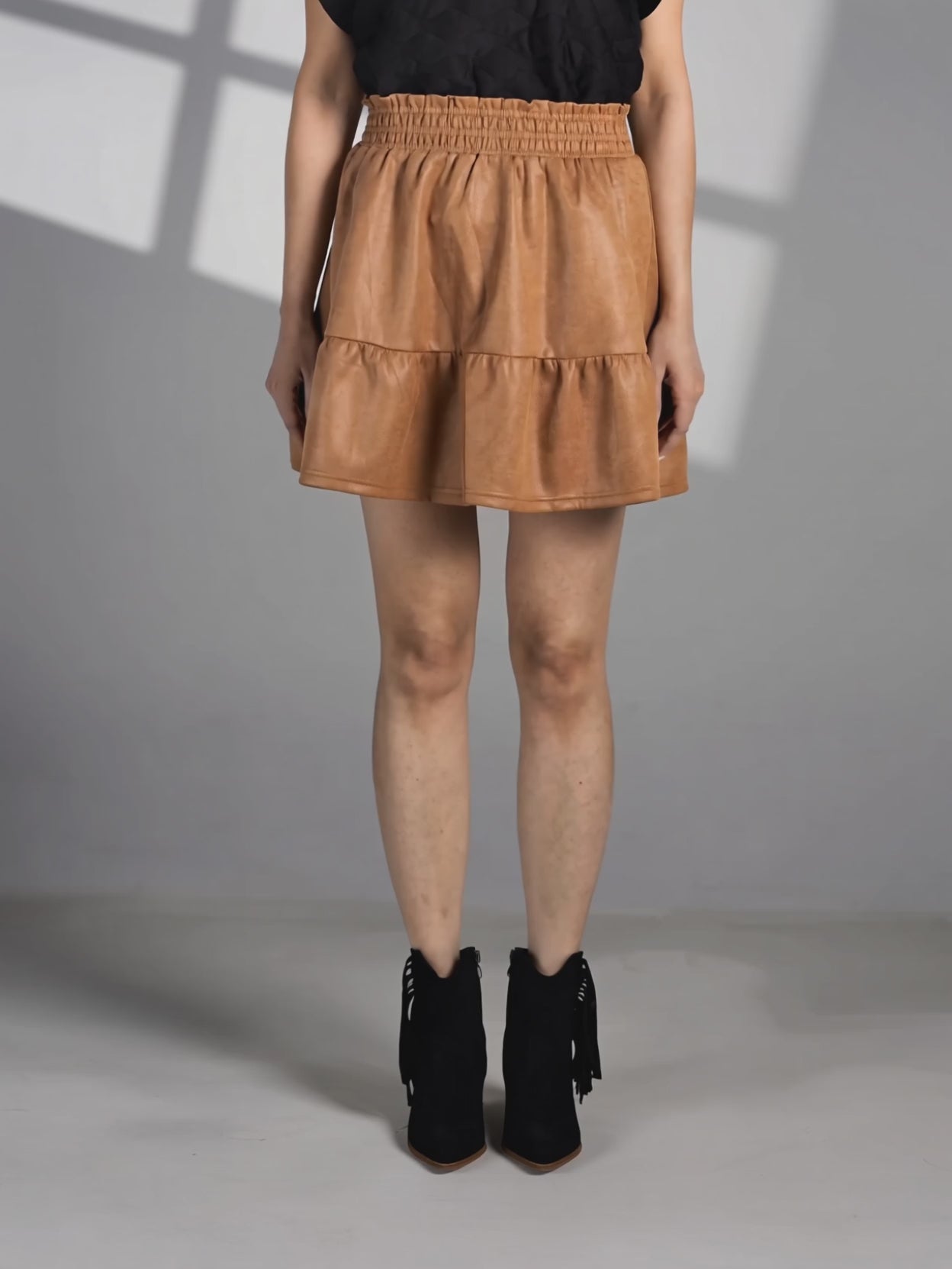 Elsa walking in the camel mini skirt to show the soft movement and sweep of its gathered flounce.
