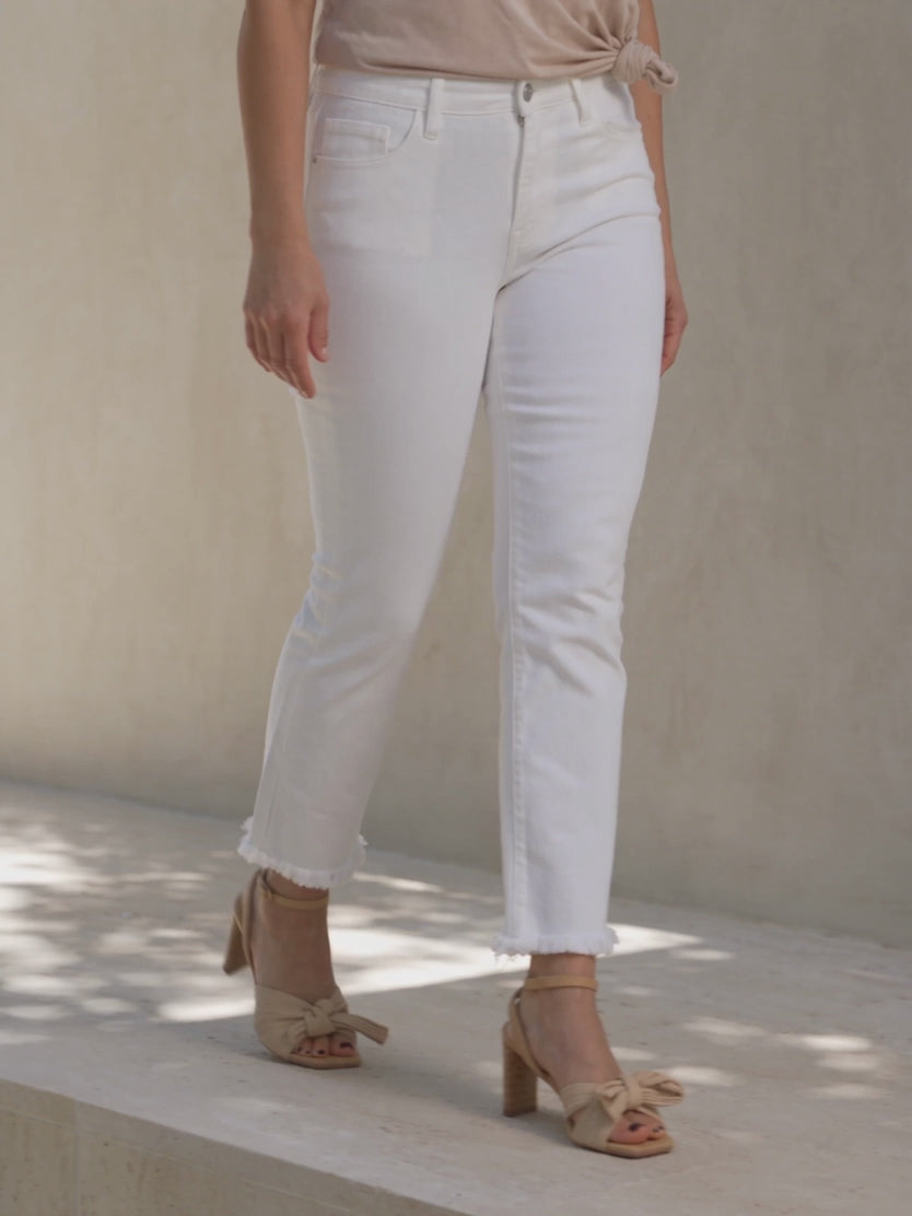 Shweta walking in All of Me white cropped jeans, showing natural knee creasing and movement at the raw hems.