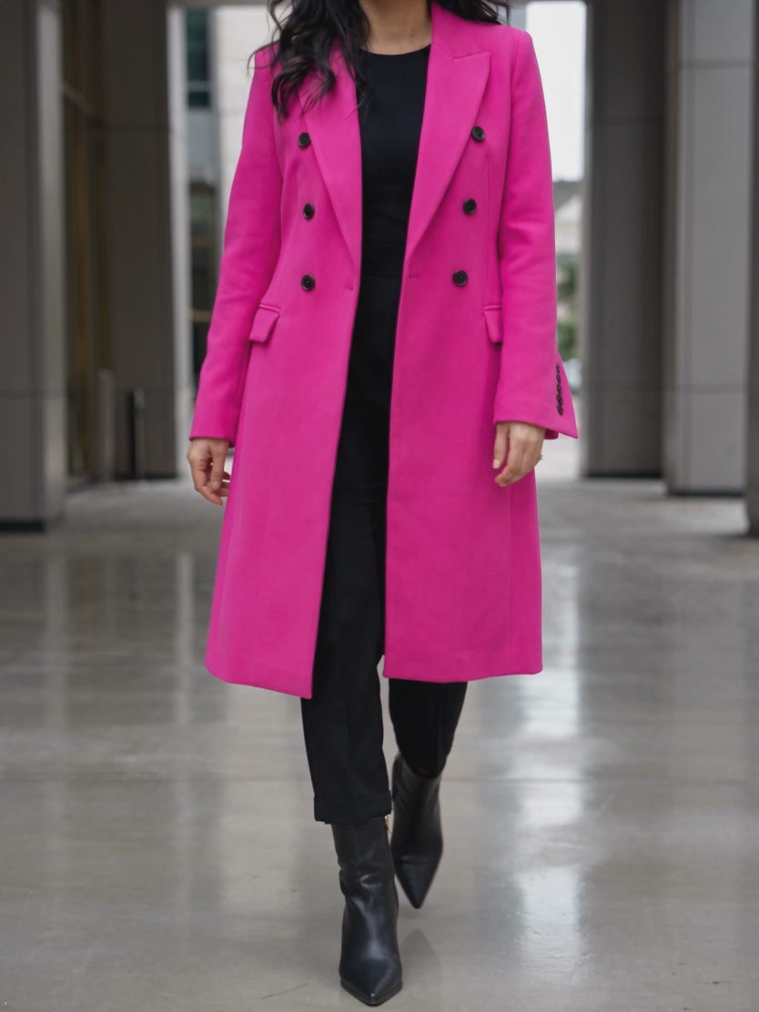 Shweta walking in the hot pink long coat, showing its controlled hem drape and movement.