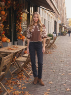 The brown embroidered faux suede top worn by Sofia at a café terrace in fall, stepping forward and turning to show the side and the fit.