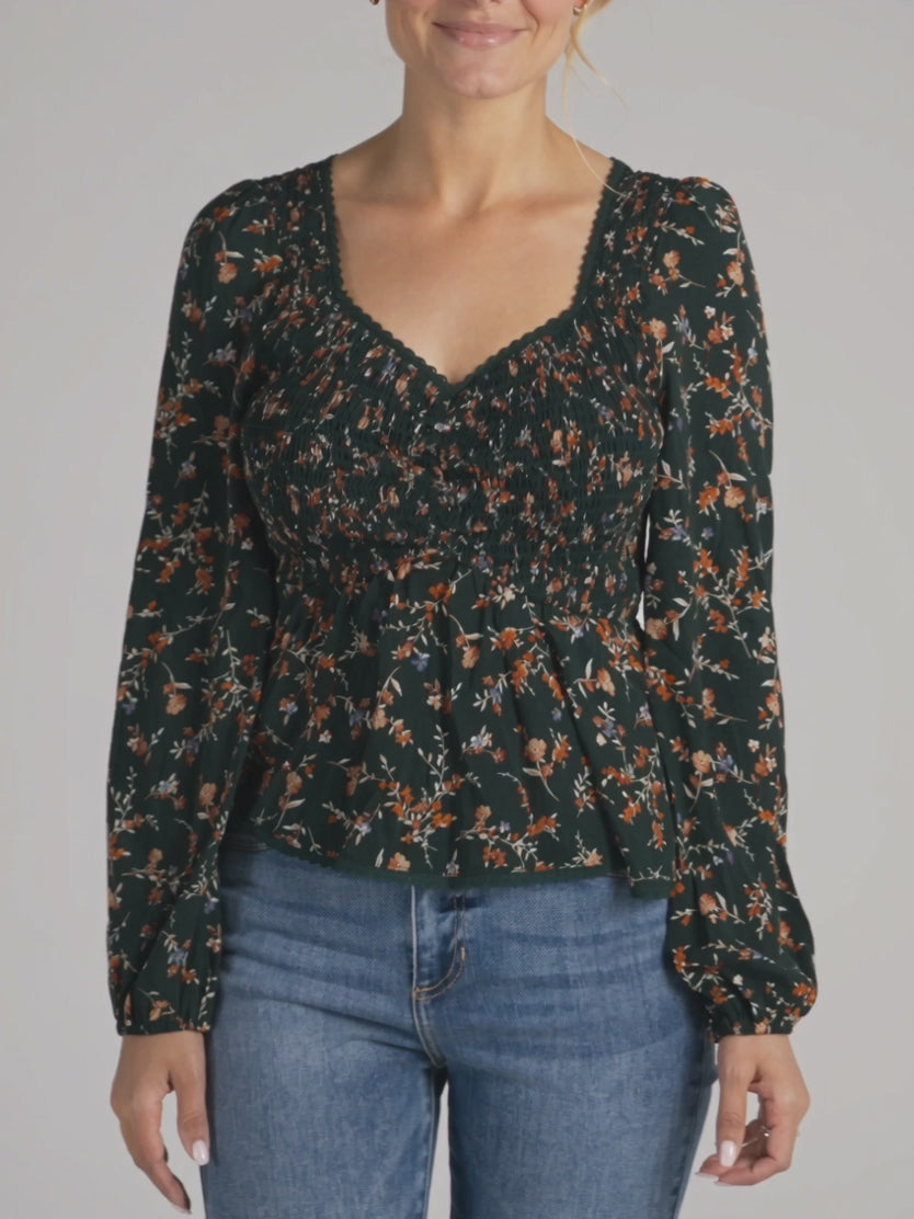 Floral peplum top in motion, showing the sleeve volume, fitted smocking and swinging hem.