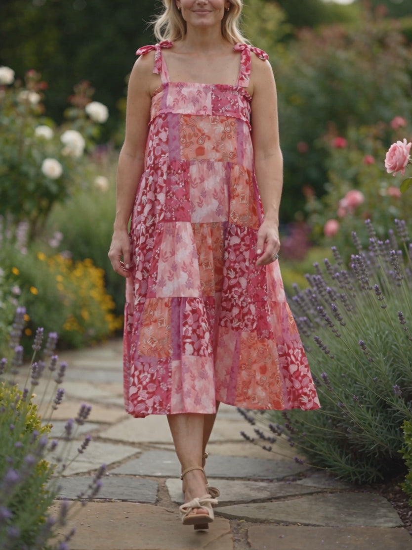 Elsa walking in the pink patchwork midi dress as its tiered skirt sways