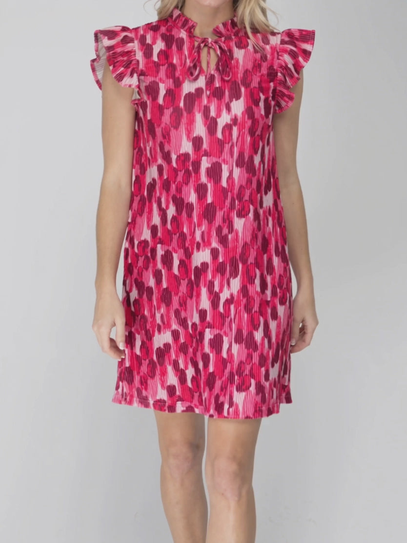 Pink pleated velvet shift dress moving as the hem swings and the layered flutter sleeves respond.
