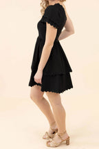 Side view of the black one-shoulder mini dress, showing the puff sleeve and the mid-thigh hem