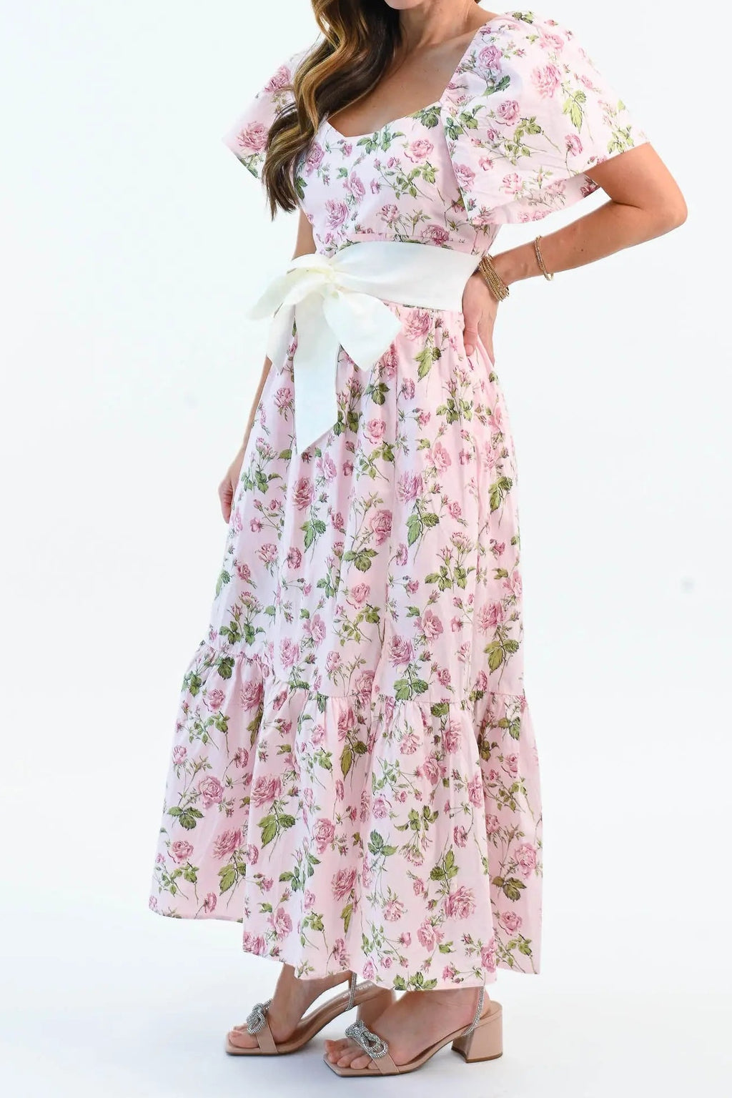 Three-quarter view of the pink rose print dress, showing the flutter sleeve, bow belt and tiered ruffle hem
