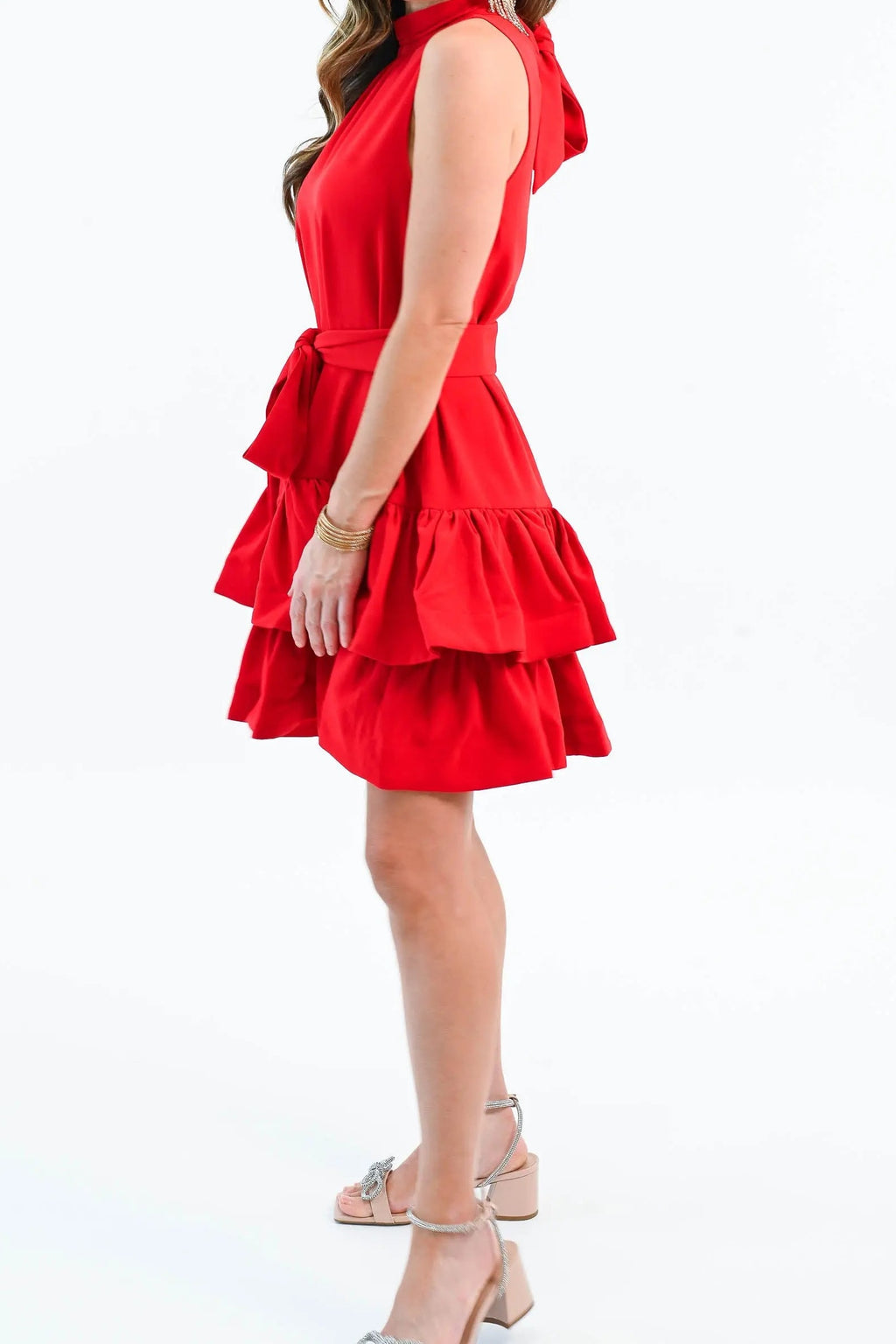 Side view of the red ruffle tiered mini dress, showing the sleeveless armhole, tie sash and mid-thigh hem