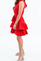 Side view of the red ruffle tiered mini dress, showing the sleeveless armhole, tie sash and mid-thigh hem