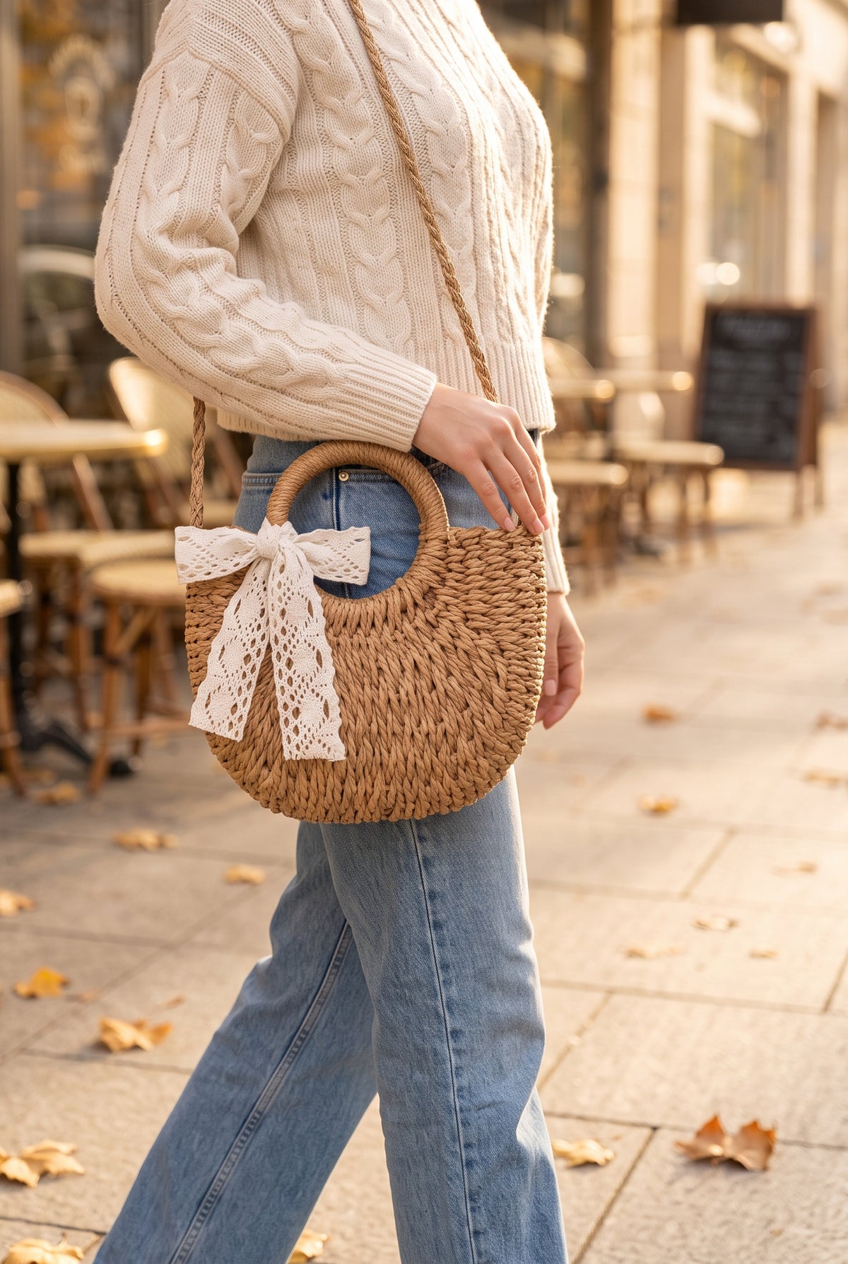 Rose Crochet Lace Straw Crossbody Bag in Tan worn crossbody at the hip with a cream knit and jeans, shown at true size