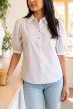 The Give It A Go striped top worn with light-wash jeans at a sunny café counter beside an iced coffee.