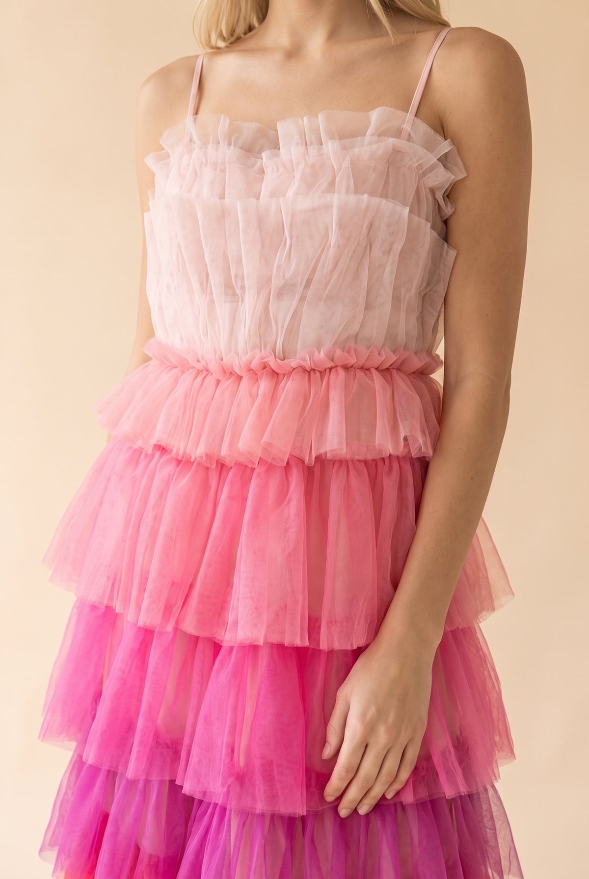 Close-up of the ruffled blush tulle bodice, thin straps and gathered pink tulle tiers