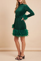 Side view of the green velvet feather trim long sleeve mini dress, showing the silhouette.