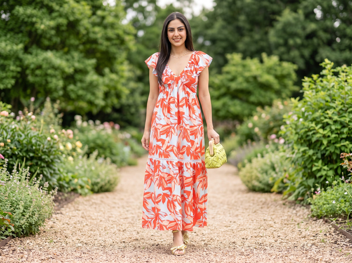 Woman in a floral maxi dress with gold bow sandals, a woven clutch and a gold pearl necklace