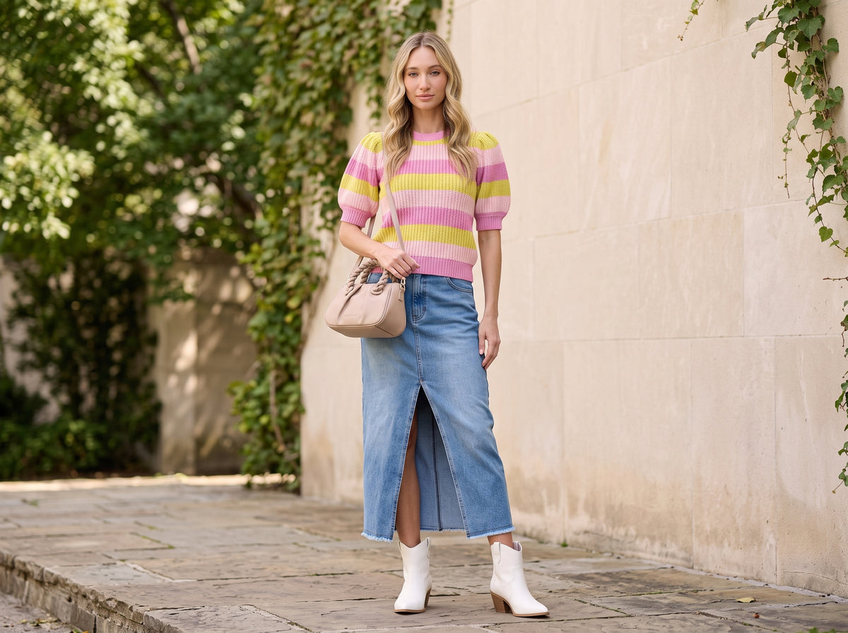 Woman in a front-slit denim midi skirt with a striped sweater, white western booties and a nude crossbody