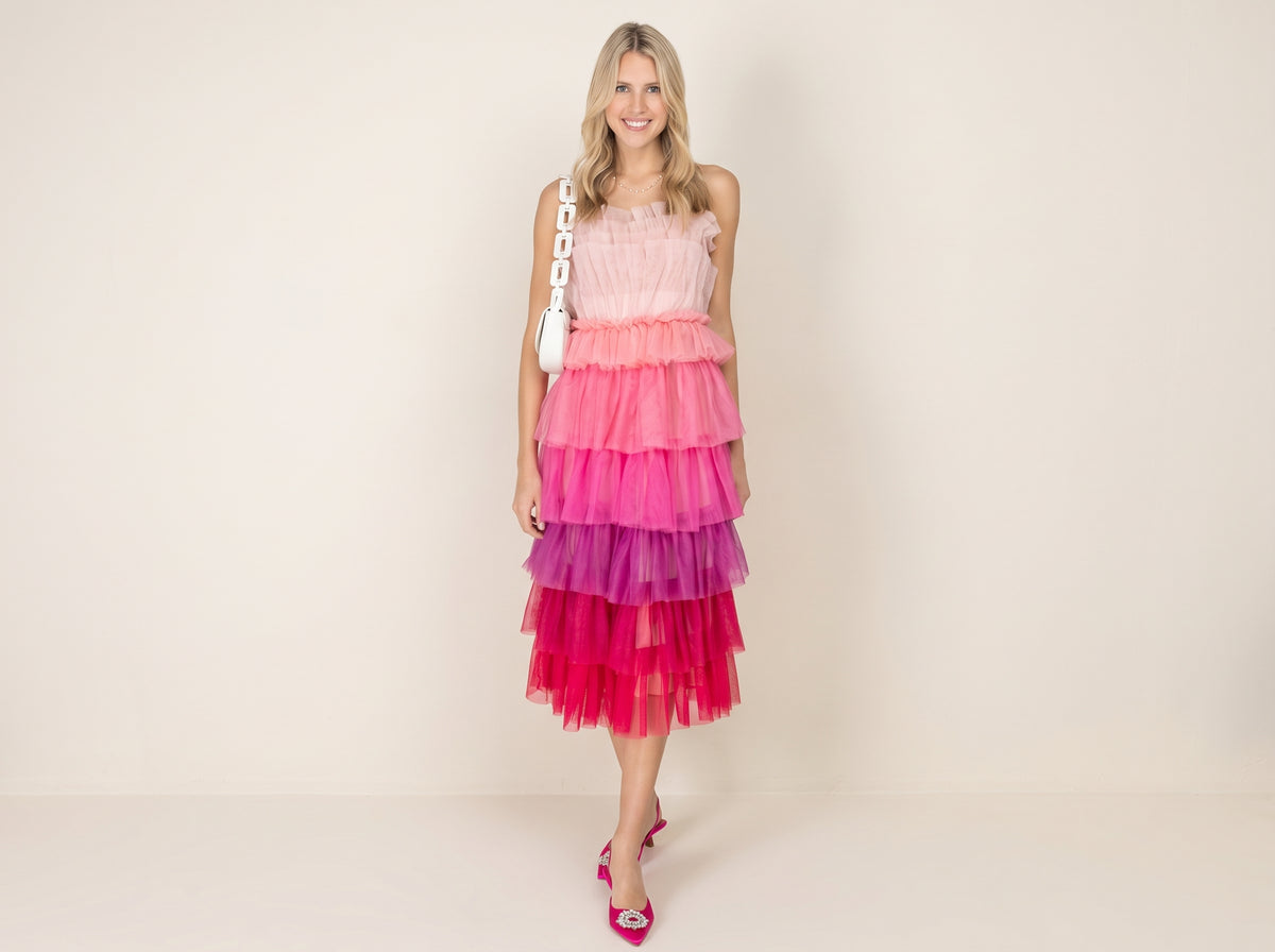Woman in a pink ombre tiered tulle midi dress with pink satin slingbacks and a white chain shoulder bag