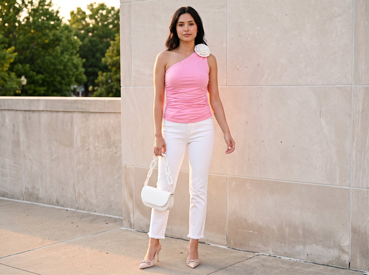 Woman in a pink ruched one-shoulder rose top with white cropped jeans, nude pumps and a white chain bag