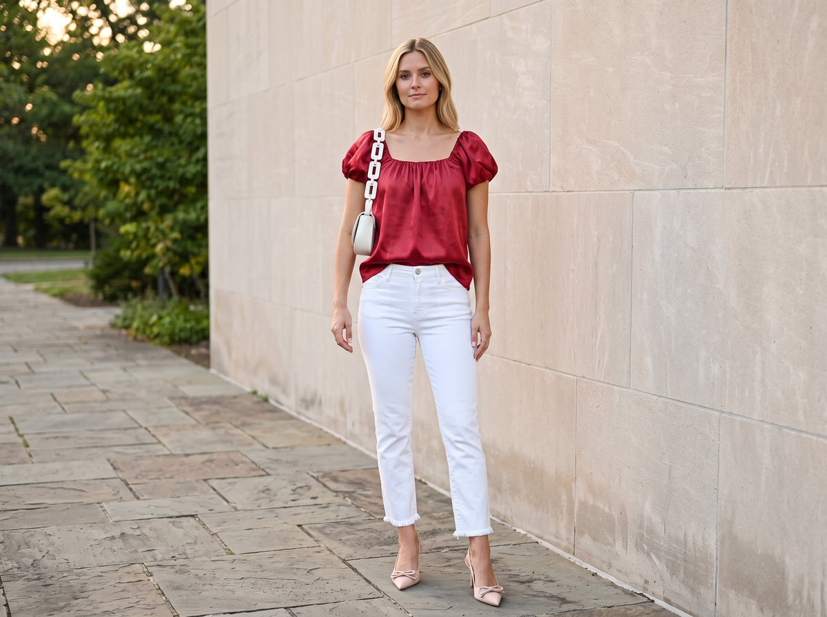 Woman in a pink satin puff-sleeve top with white cropped jeans, nude pumps and a white chain bag