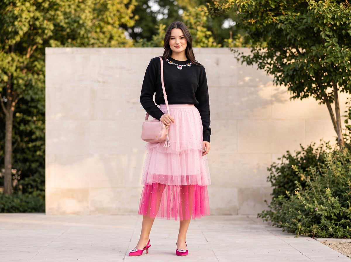 Woman in a pink tiered tulle midi skirt with a black embellished sweater, pink slingbacks and a pink crossbody