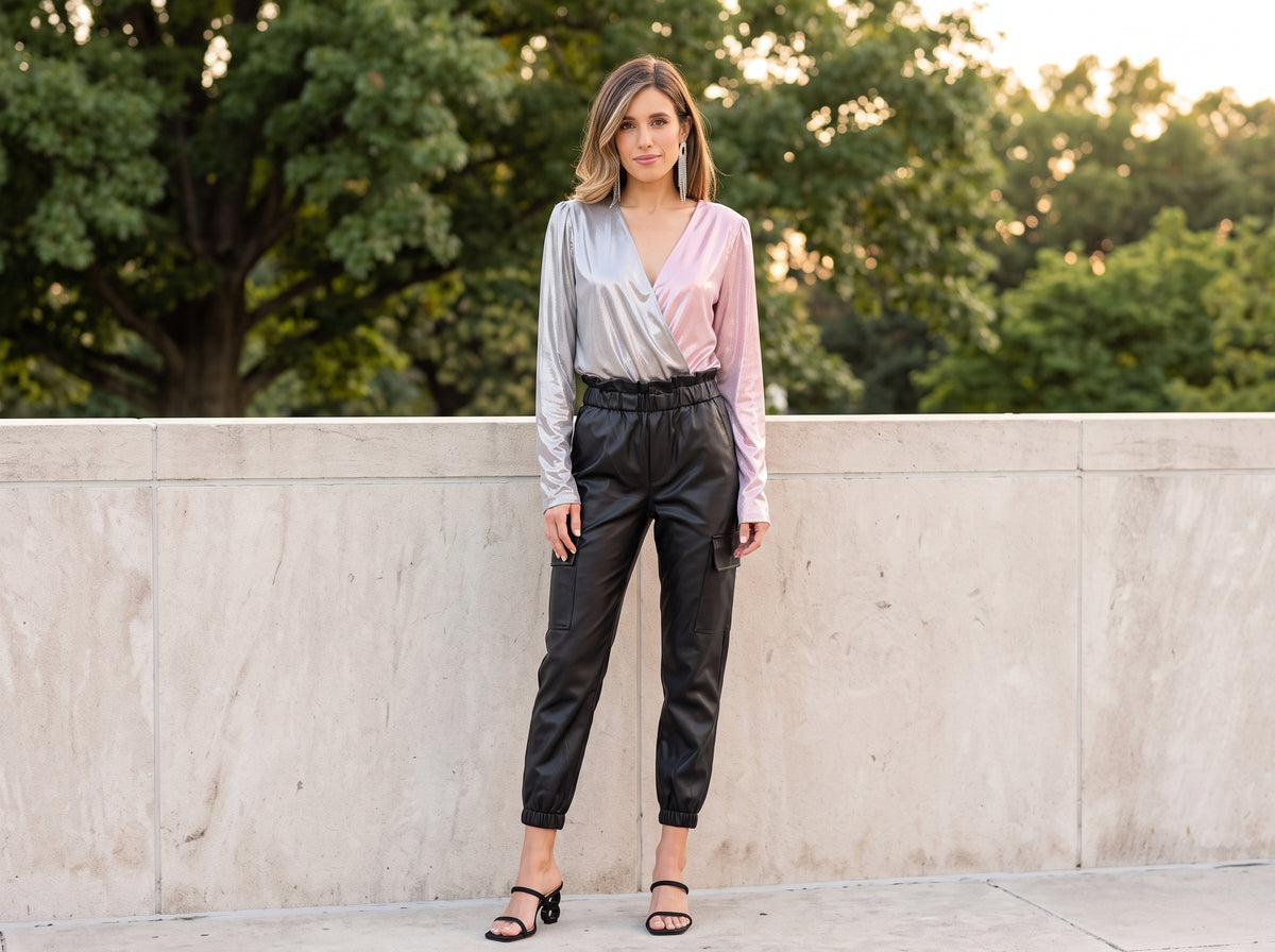 Woman in a silver and pink shimmer bodysuit with black faux leather joggers, black heeled sandals and silver earrings