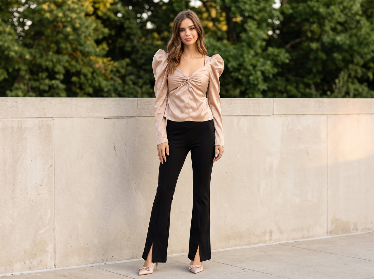 Woman in black ponte flare pants with a champagne puff-sleeve top, nude pumps and a pearl necklace