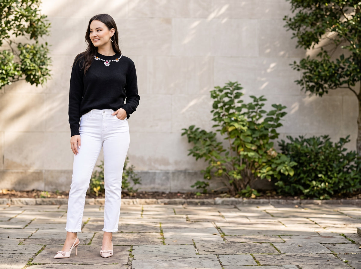 Woman in white cropped straight jeans with a black embellished sweater, nude pumps and gold bow hoops