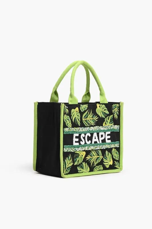 A tropical-themed tote bag featuring green leaf embroidery, sequin "ESCAPE" lettering, fabric-wrapped handles, and a detachable crossbody strap.
