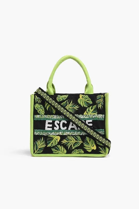 A tropical-themed tote bag featuring green leaf embroidery, sequin "ESCAPE" lettering, fabric-wrapped handles, and a detachable crossbody strap.