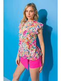 Model wearing a floral ruffle sleeve high neck top with vibrant colors against a blue background.