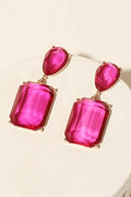 Bold pink gemstone statement drop earrings with gold-plated metal setting displayed on a jewelry stand.